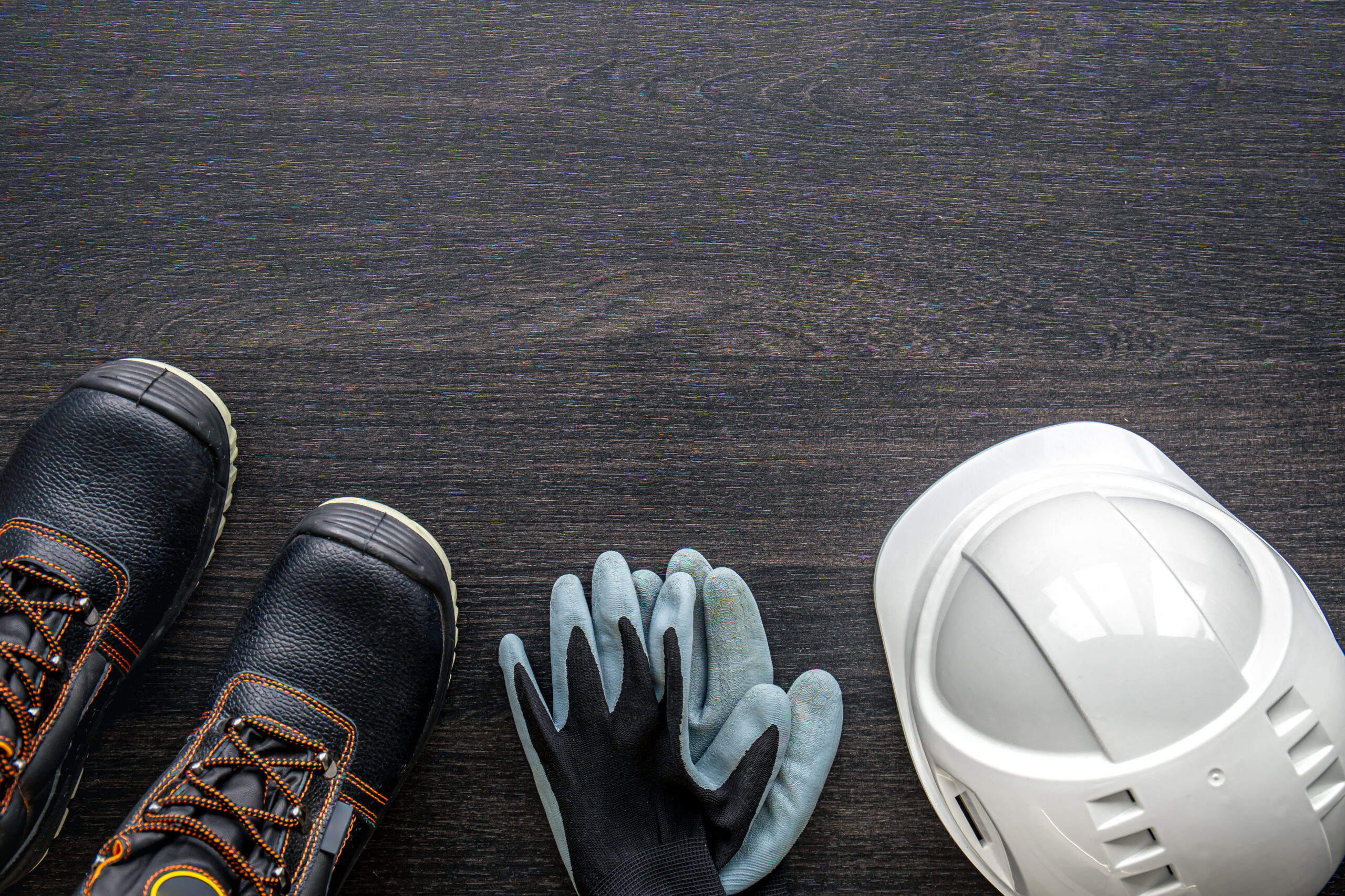 Electrician work uniform items on a wooden background, top view.